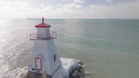 A-serene-Southampton-lighthouse-on-a-calm-lake-with-melting-ice,-under-clear-skies,-aerial-view