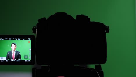 camera record professional asian male anchor reporting on green screen at home studio. chroma key template background