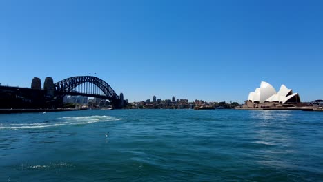 tracking shot of sydney harbour bridge and sydney opera house on the water