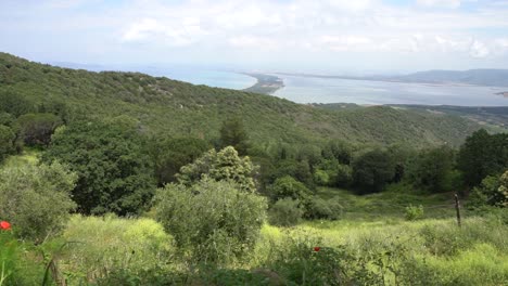 Una-Hermosa-Toma-Panorámica-A-Través-De-La-Bahía-De-Orbetello-Y-Albanés-De-Monte-Argentario-En-Italia-Con-Mariposas-Volando