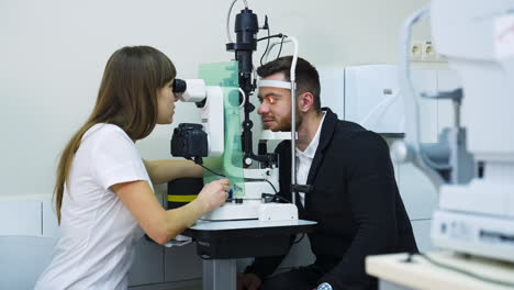ophthalmologist check eyesight of man. ophthalmologist checking eyesight of young man with modern equipment