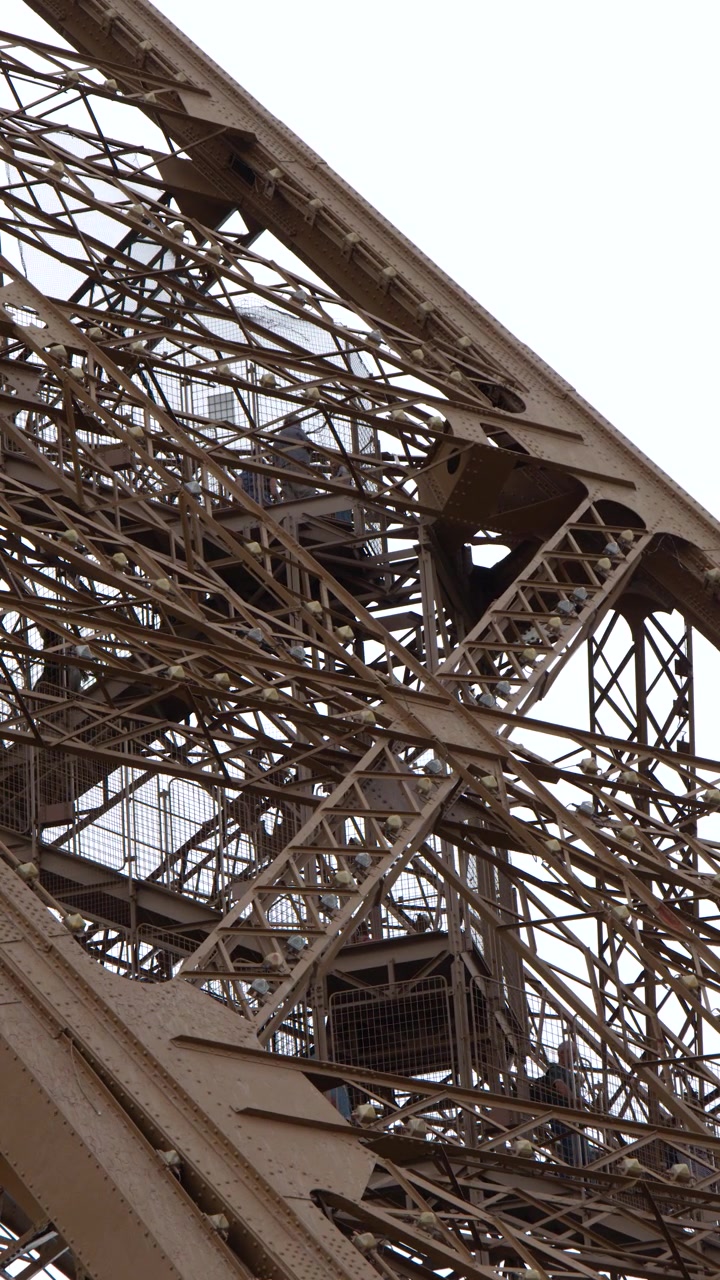Close-up View of Eiffel Tower's Intricate Iron Structure with Tourists