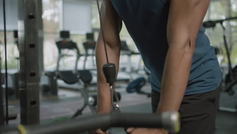 vista de cerca de las manos del hombre afroamericano sosteniendo las manijas del cable de la máquina de gimnasia