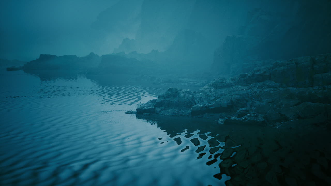 Misty coastal landscape with rocky shoreline and calm water reflections