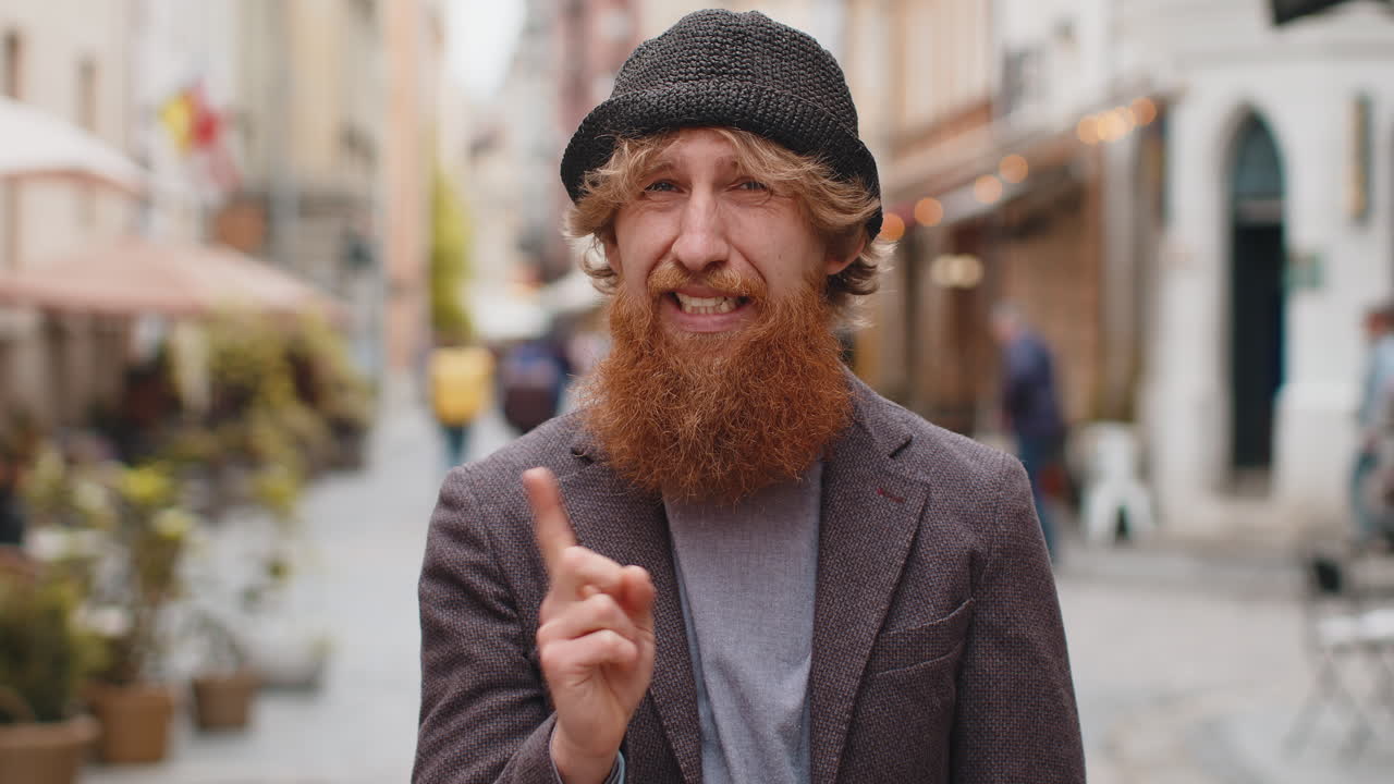 Displeased upset young bearded man reacting to unpleasant awful idea wave hand finger shake head no