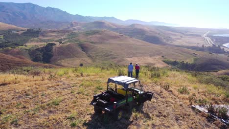 antena de un hombre y una mujer jubilados de pie junto a atv en la magnífica vista de la costa de la costa de gaviota, el océano pacífico y el condado de santa bárbara, california 1