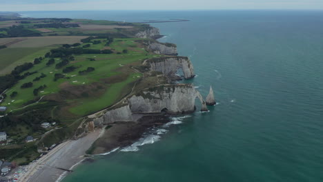 Etretat-Cliff-Arches-Establishing-Shot-from-high-angle-view,-Aerial-forward-on-Cloudy-Day