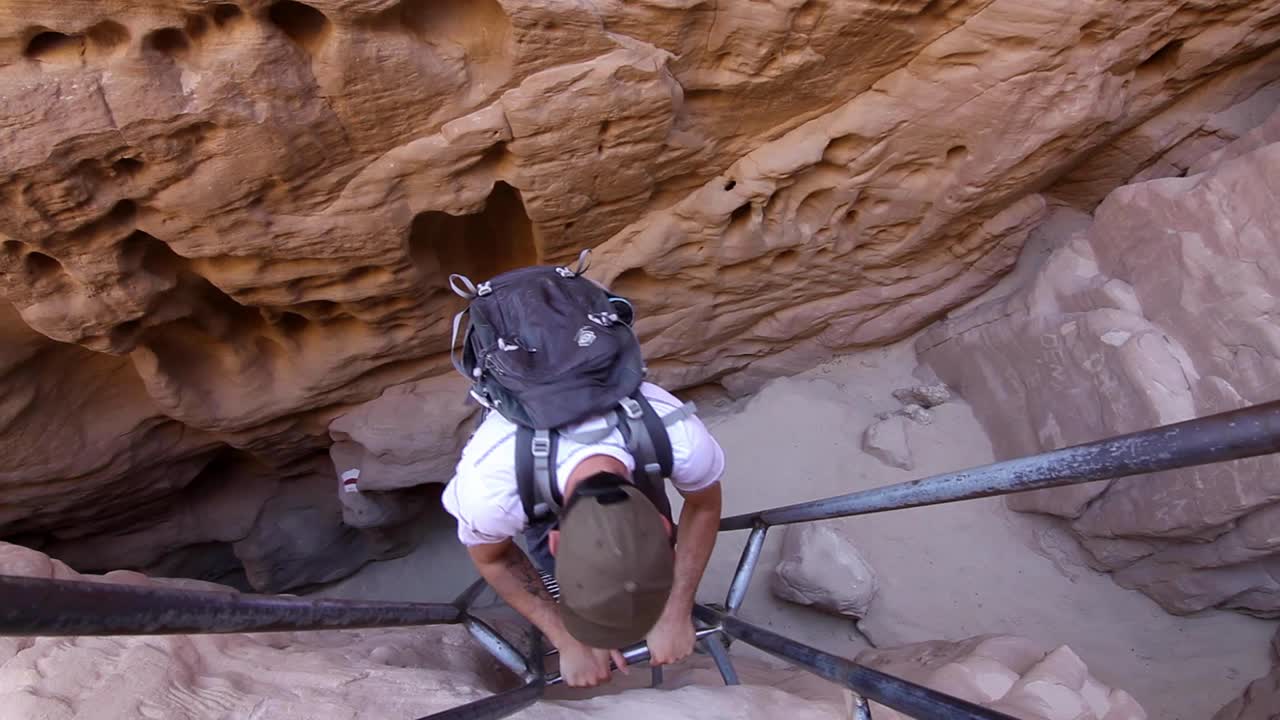 aventurero bajando escaleras en el valle, desierto de israel, tiro de gran angular