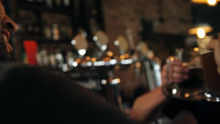 Due uomini che brindano con boccali di birra al bar, una mano che entra da sinistra avviando una grafica tecnologica che si espande e svanisce