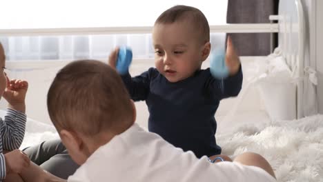 baby triplets sitting together in bedroom and playing with toys