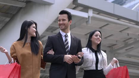 handsome man take woman shopping together in city. lady holding shopping bag on hands.