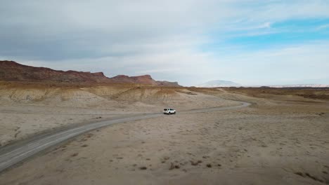 drone flies over a car driving thru smoky mountain towards alstrom point, lake powell