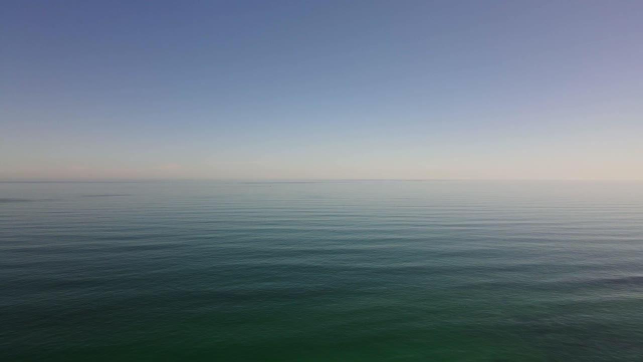 아무것도 보이지 않는 넓은 바다 위로 높이 날아가는 드론 샷