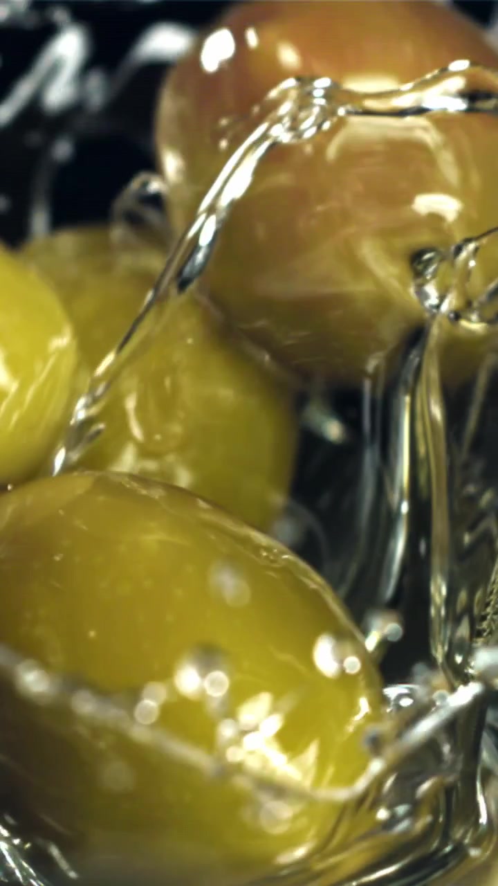 Olive verdi fresche che schizzano nell'acqua al rallentatore