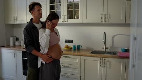 mujer embarazada morena feliz bailando con su marido en la cocina por la mañana