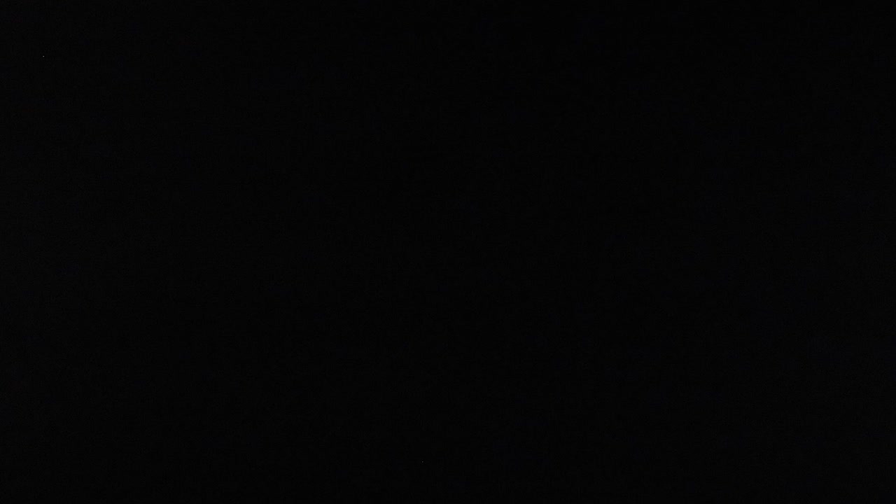 Bright tennis balls aligned in a grid against a dark backdrop, showcasing symmetry and contrast.