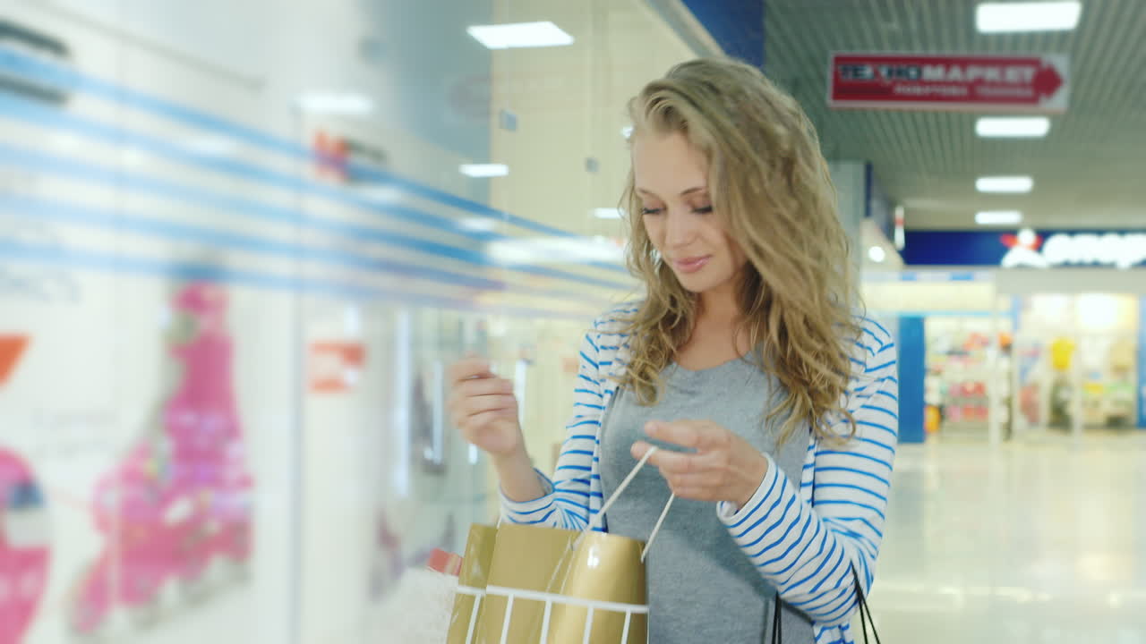 mujer joven modelando apariencia con bolsas para ir de compras es el centro comercial que mira las compras que están en