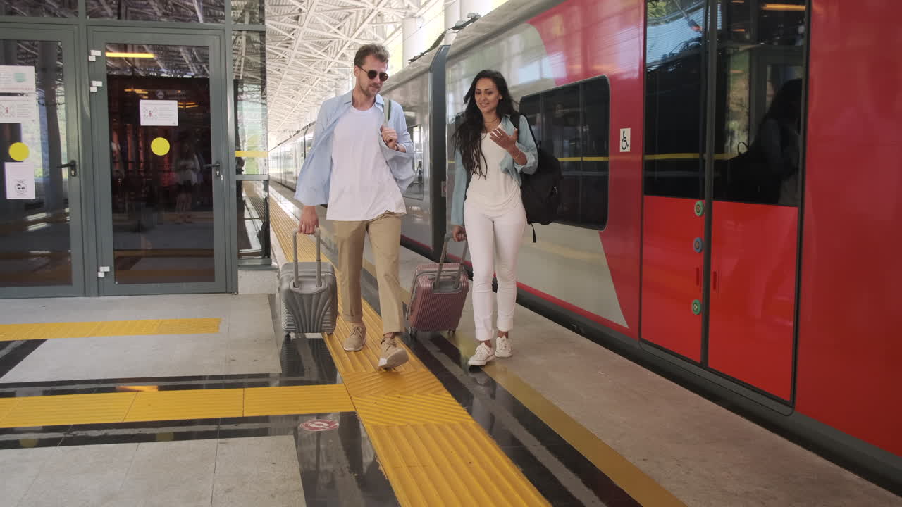 pareja caminando por la estación de tren con equipaje