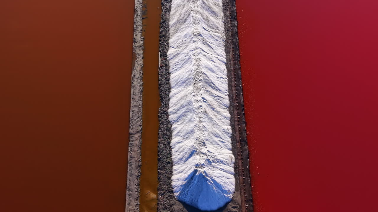 Le vivaci saline mostrano contrasti mozzafiato tra le acque di un rosso intenso e i brillanti cumuli di sale bianco al tramonto, creando un'opera d'arte naturale unica.
