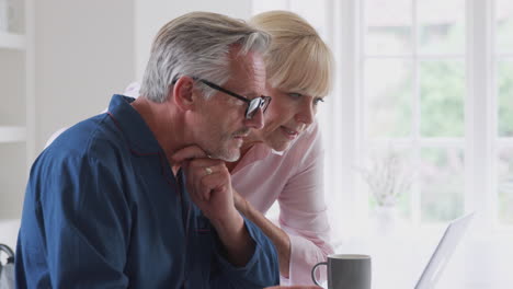 senior couple with man in wheelchair looking up information about medication online using laptop