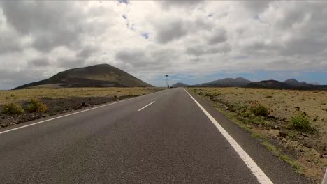 long distanced road winding through desolate hills under a dramatic sky, canarias, lanzarote, spain.