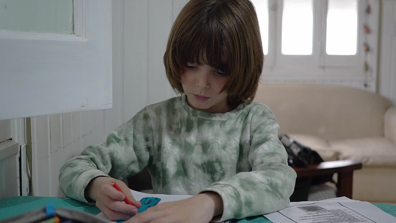 Close view of a little oy drawing a line with a ruler as part of his homework.