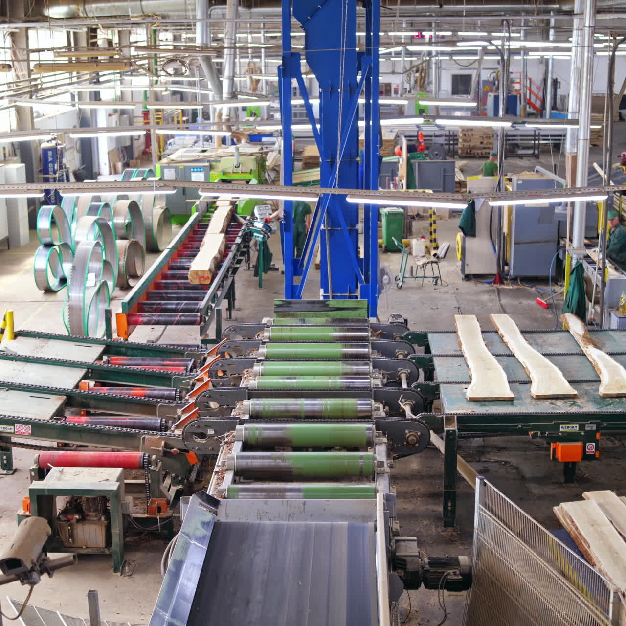 Woodworking factory indoors. Workers control the process of making boards by automated equipment. Power-saw bench.