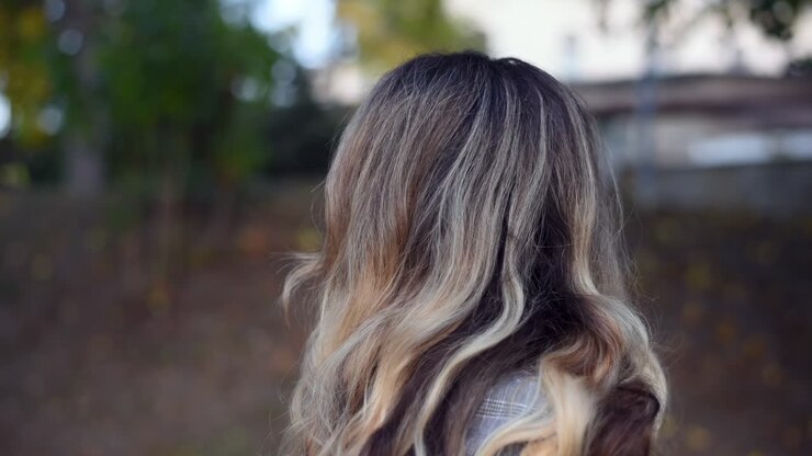 Primo piano di una donna bionda che si volta e sorride alla fotocamera nel parco