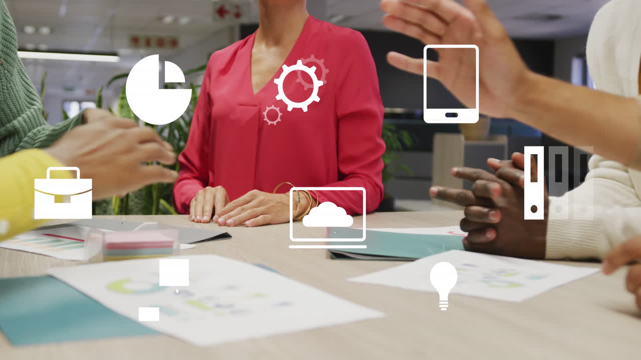 Animation of digital icons over mid section of colleagues stacking their hands together at office