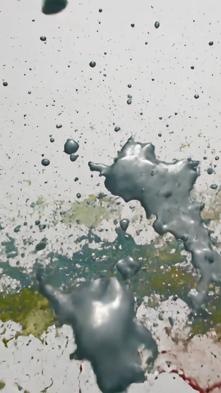 Vertical video: Colliding rainbow paint with silver over white backdrop, creating droplets