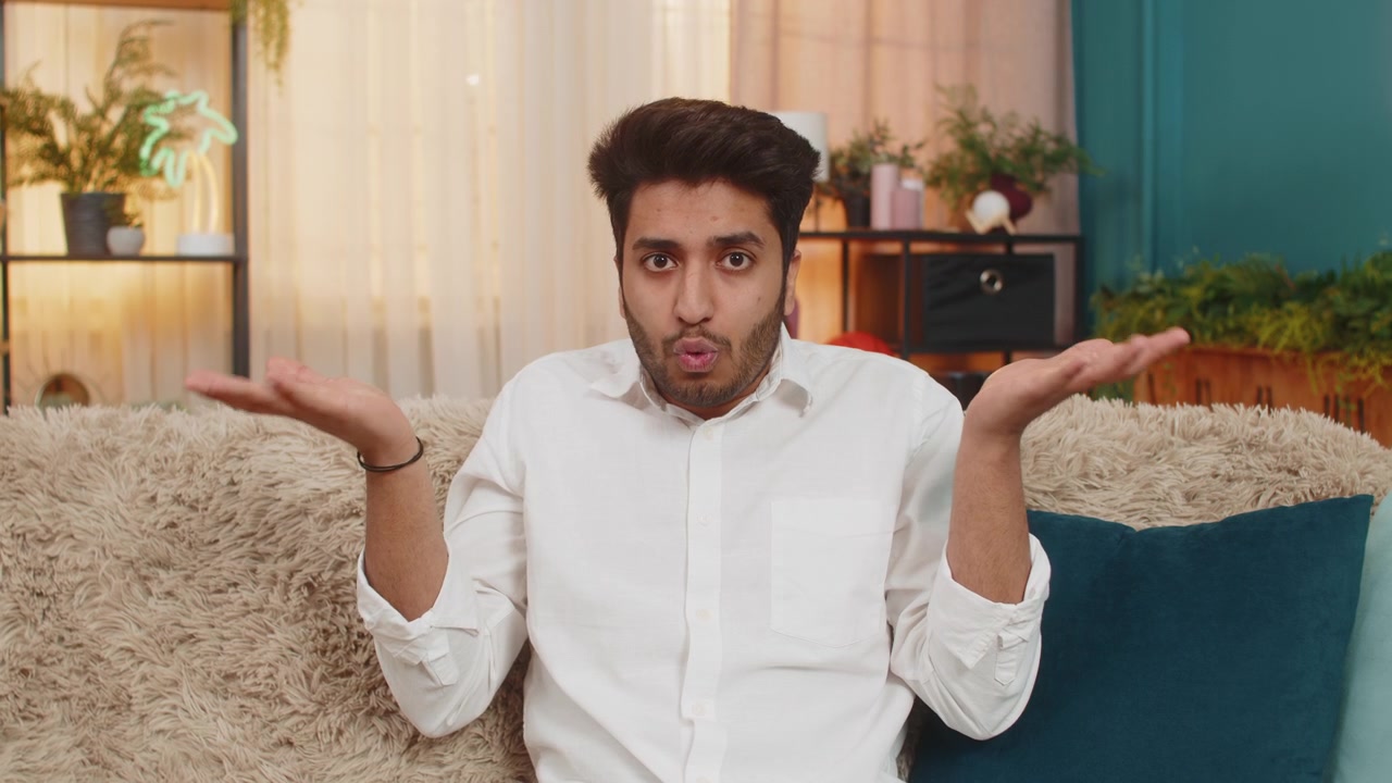 Indian young man surprised raising hands in confusion making what why gesture questioning reaction