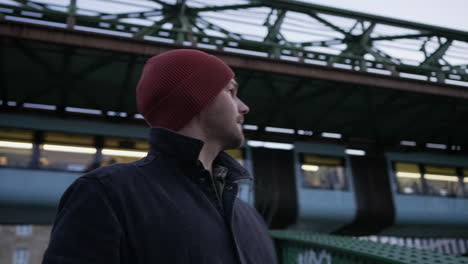 solitary man wandering in wuppertal gazing at suspended train passing by, germany