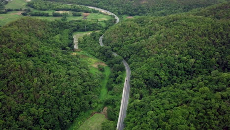 logistic concept aerial view of countryside road passing through the lush greenery and foliage tropical rain forest mountain landscape
