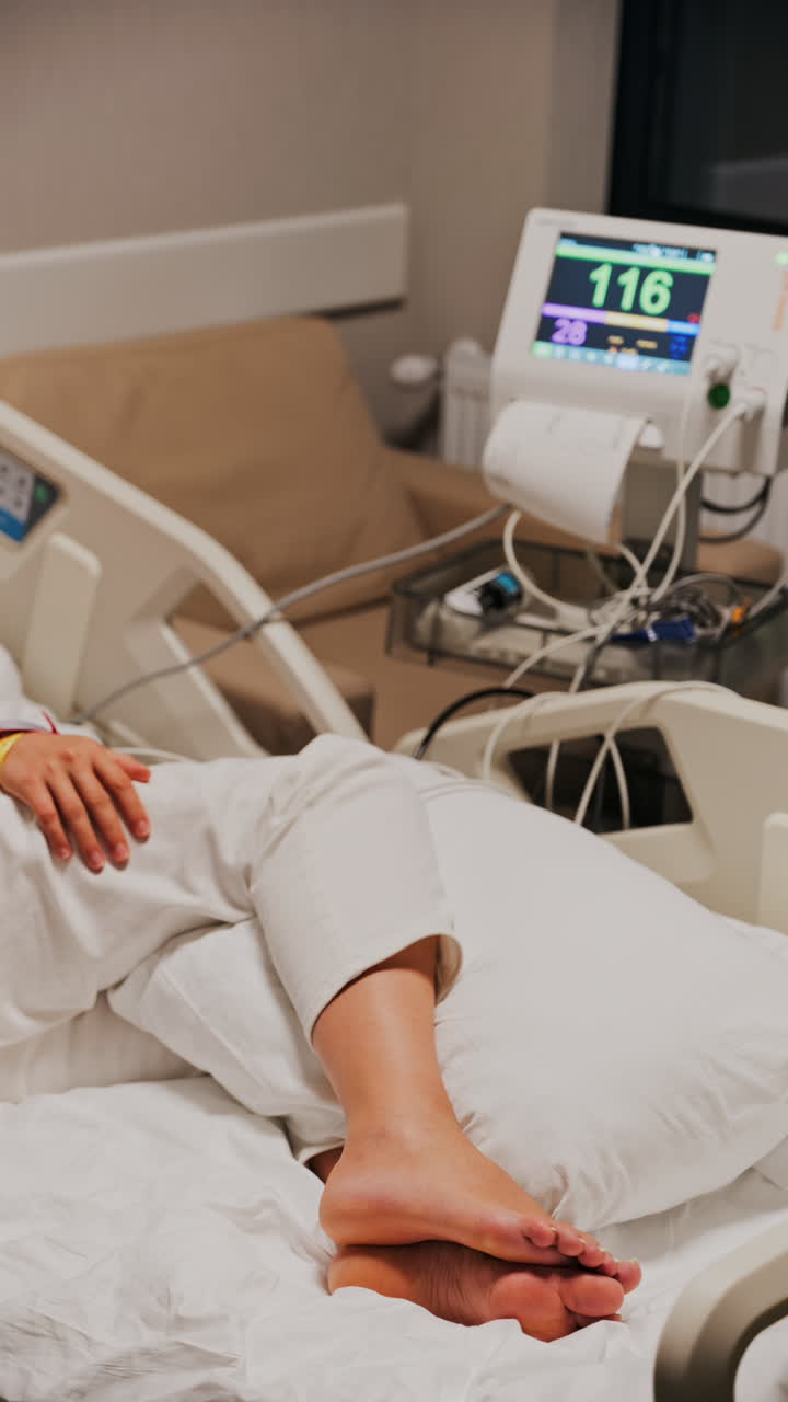 Pregnant woman lying in a hospital bed during a prenatal check-up at the doctor's office. Vertical