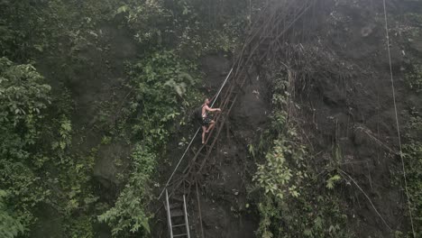 aerial orbits man climbing steep stairway in hazy jungle canyon, java