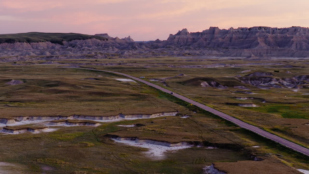 Endless Road Stretching Through Rugged Badlands Captured at Sunset Glow