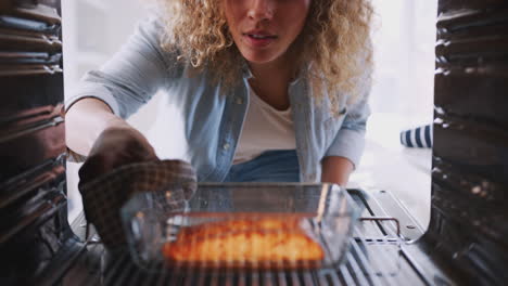 view looking out from inside oven as woman cooks oven baked salmon