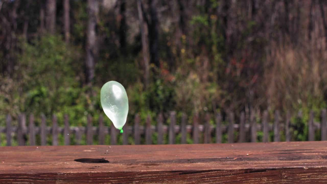 녹색 물풍선이 나무 벤치에서 네 번 튕긴다