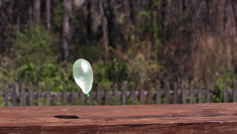 un globo de agua verde rebota en un banco de madera cuatro veces