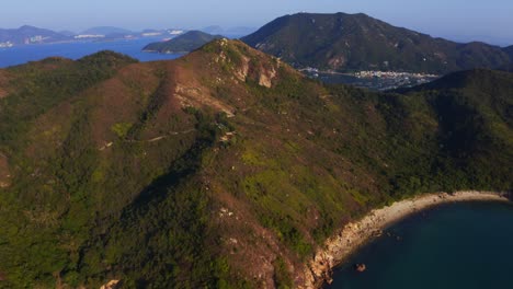 Drone-shot-going-forward-to-a-mountain-covered-by-short-trees-during-the-day