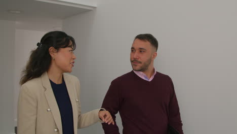 male and female teachers talking as they walk along corridor in school building together