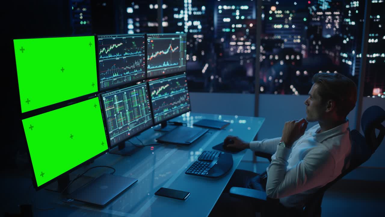 analista financiero que trabaja en una computadora con estación de trabajo multi-monitor con pantalla verde chroma key mock up plantilla y gráficos de acciones en tiempo real. hombre de negocios trabaja en un banco de inversión por la noche.