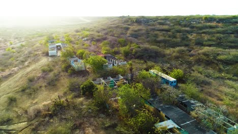 Antigua-Construcción-Cubierta-De-Maleza-Abandonada-Sitio-De-Construcción-De-Viviendas-En-Medio-Del-Paisaje-De-Matorral-Desértico-En-La-Ladera,-Curacao