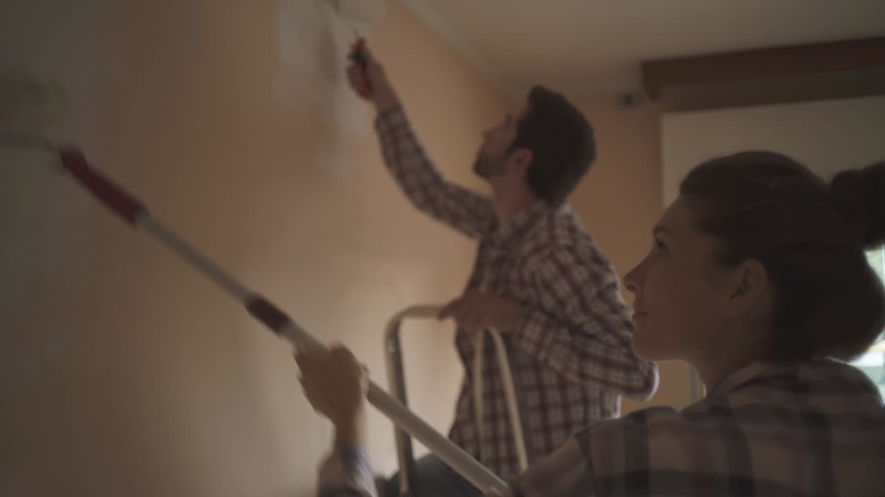 pareja pintando paredes juntos en su nueva casa