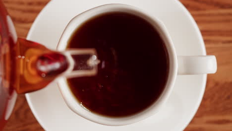 overhead view of liquid being poured from a bottle into a cup