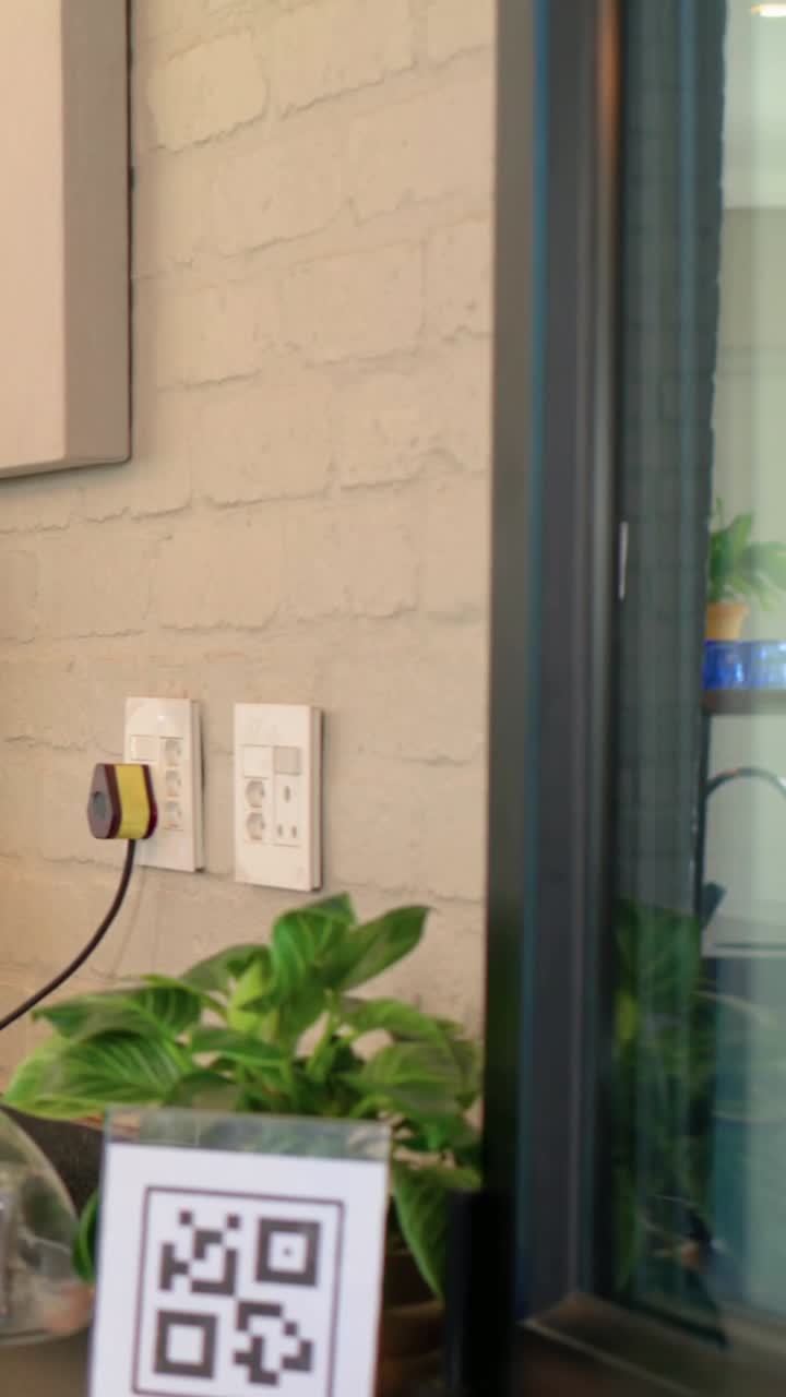 Vertical video: Entering woman in yellow knit holding box at cafe, showing QR sign, copy space