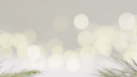 Video-of-close-up-of-bokeh-christmas-fairy-lights-and-pine-tree-branches-on-grey-background