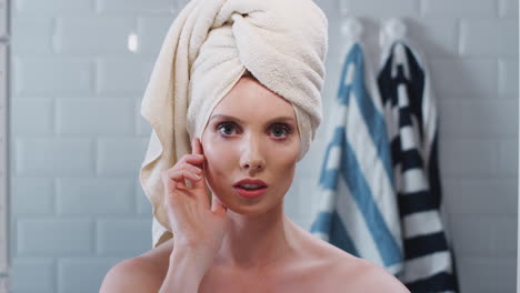 view as though reflected in bathroom mirror of young woman with towelling turban getting ready in the morning