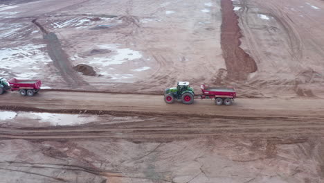 drone footage following a tractor with empty trailer on a construction site