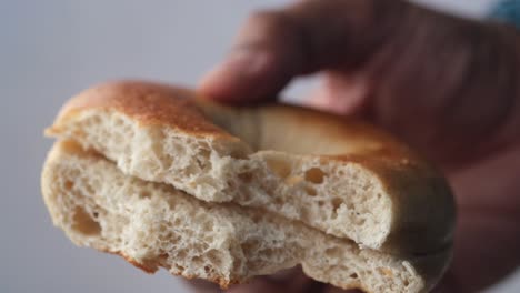 holding half eaten fresh bagel bread